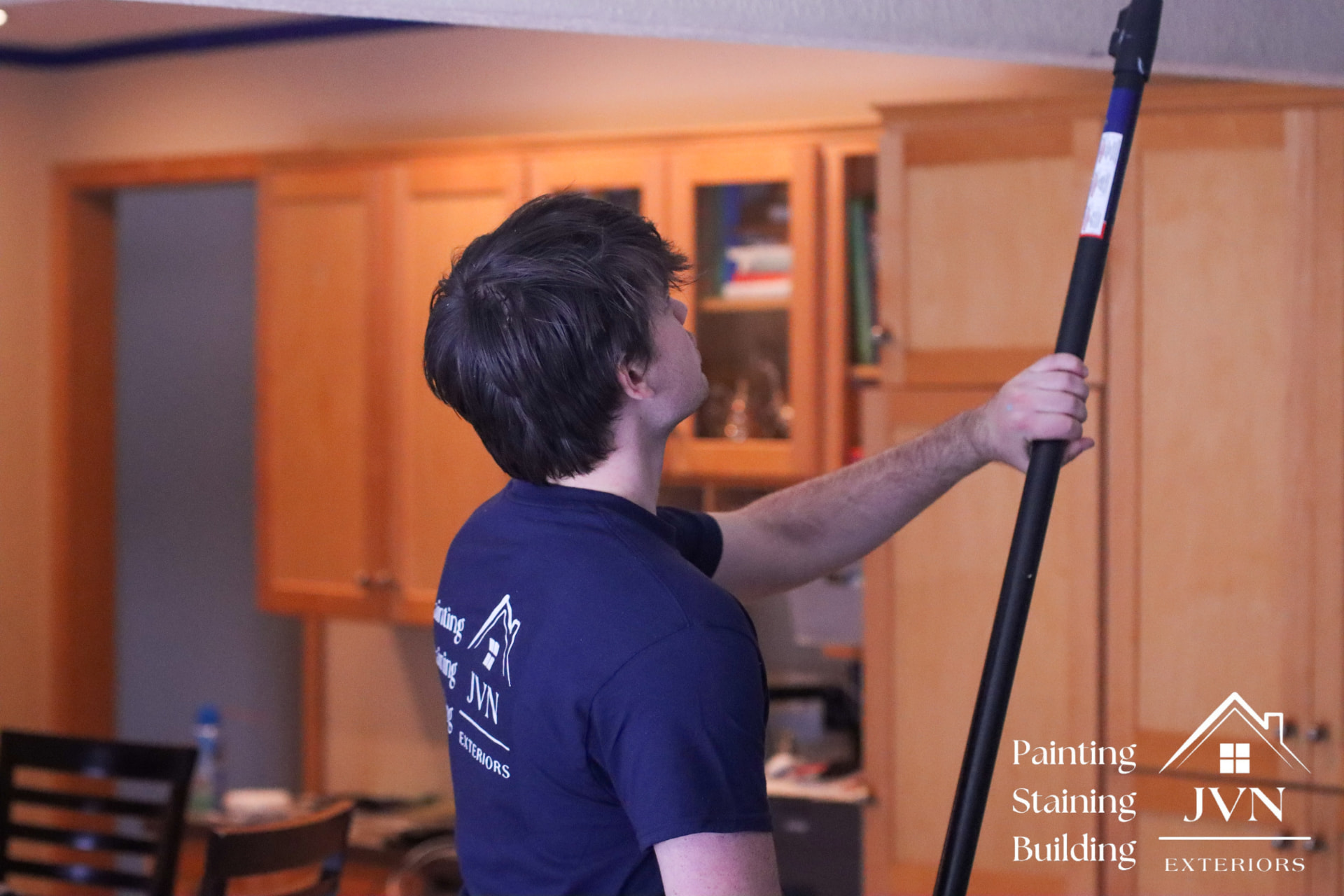 JVN Exteriors painter working in an Edina, MN kitchen alongside wood cabinets