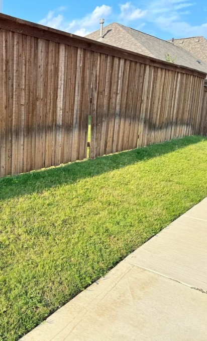 Wood privacy fence in Edina, MN with dark water stain line from sprinkler run-off along the lower boards