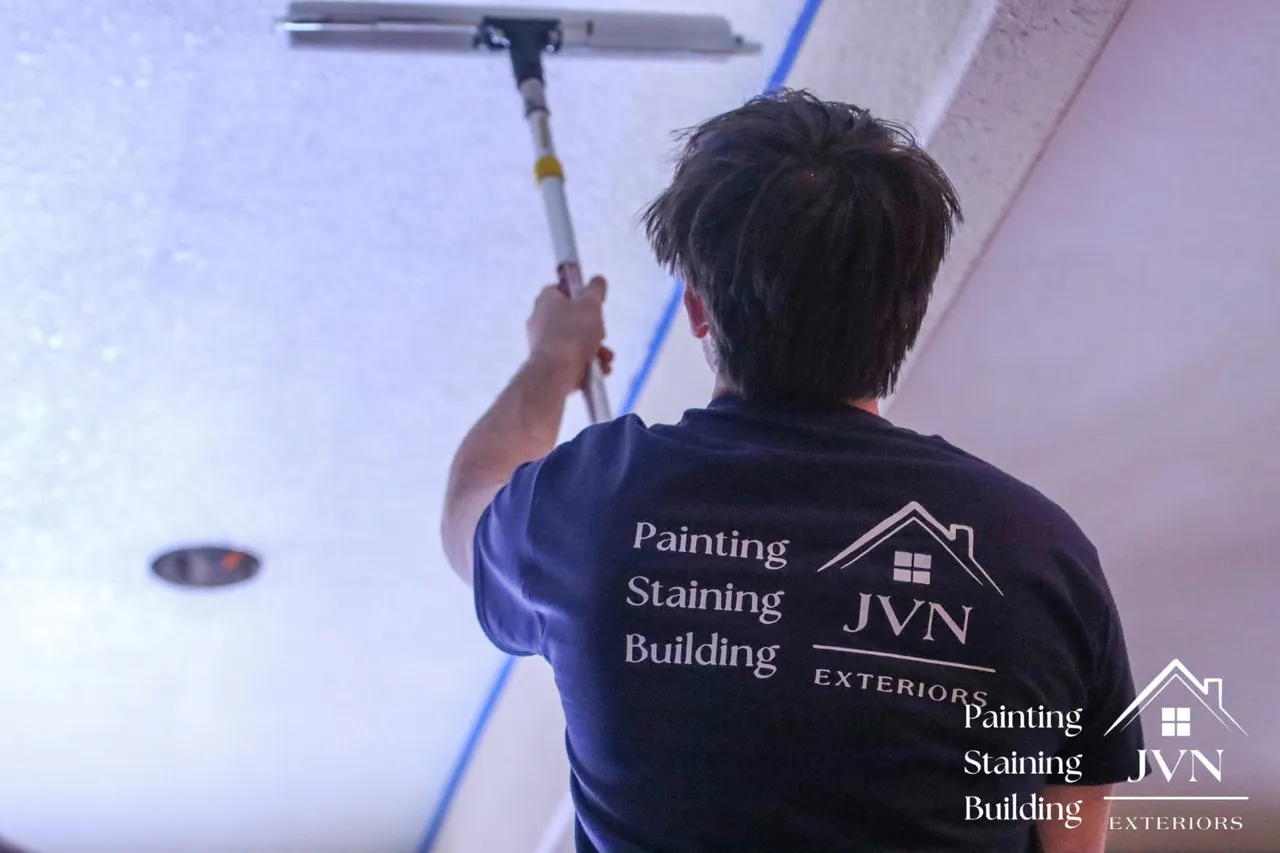 JVN Exteriors painter rolling a textured ceiling with a taped edge for a clean line