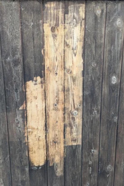 Wood privacy fence panels in Edina, MN showing stripped areas where old dark finish has been removed to expose bare wood underneath