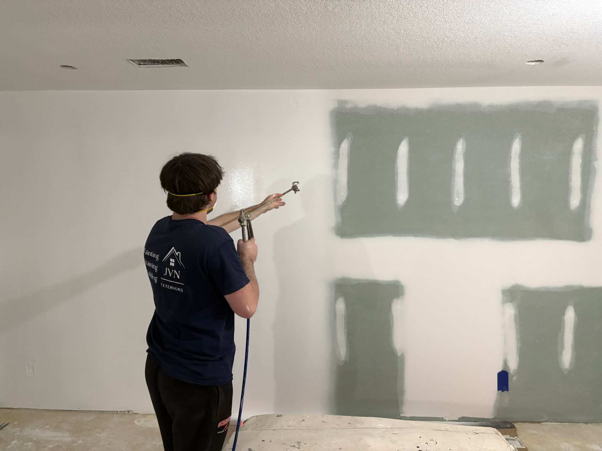 JVN Exteriors painter spraying interior walls inside a heated Edina, MN home in winter