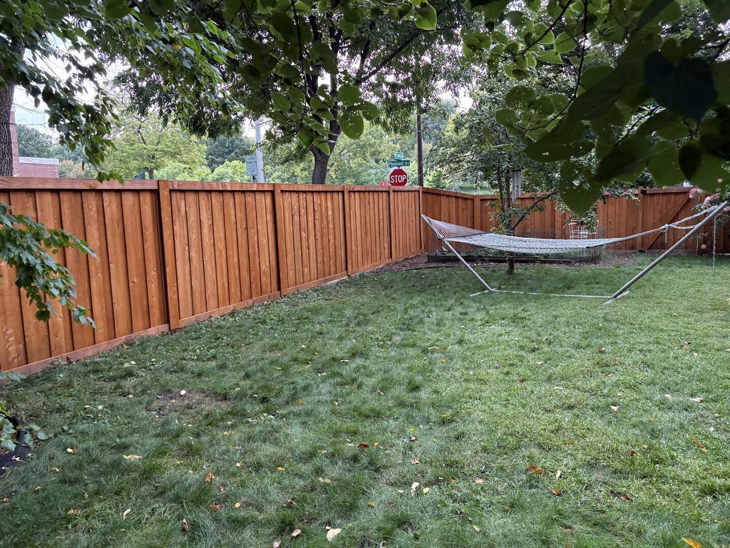 Stained cedar wood privacy fence in an Edina, MN backyard with green lawn, trees, and hammock stand showing the yard-facing side