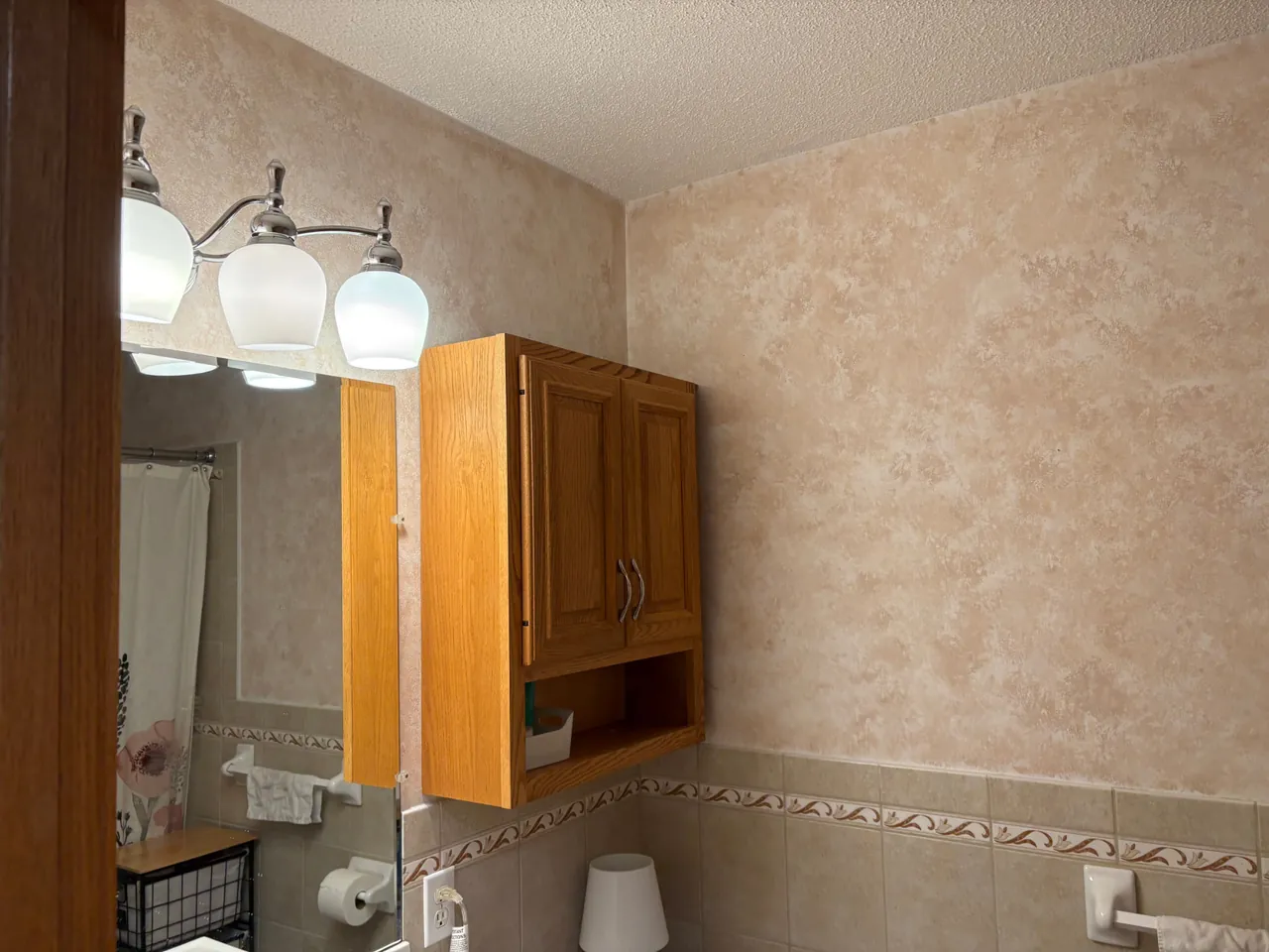Powder room with dated sponge-painted walls and an oak cabinet before interior painting